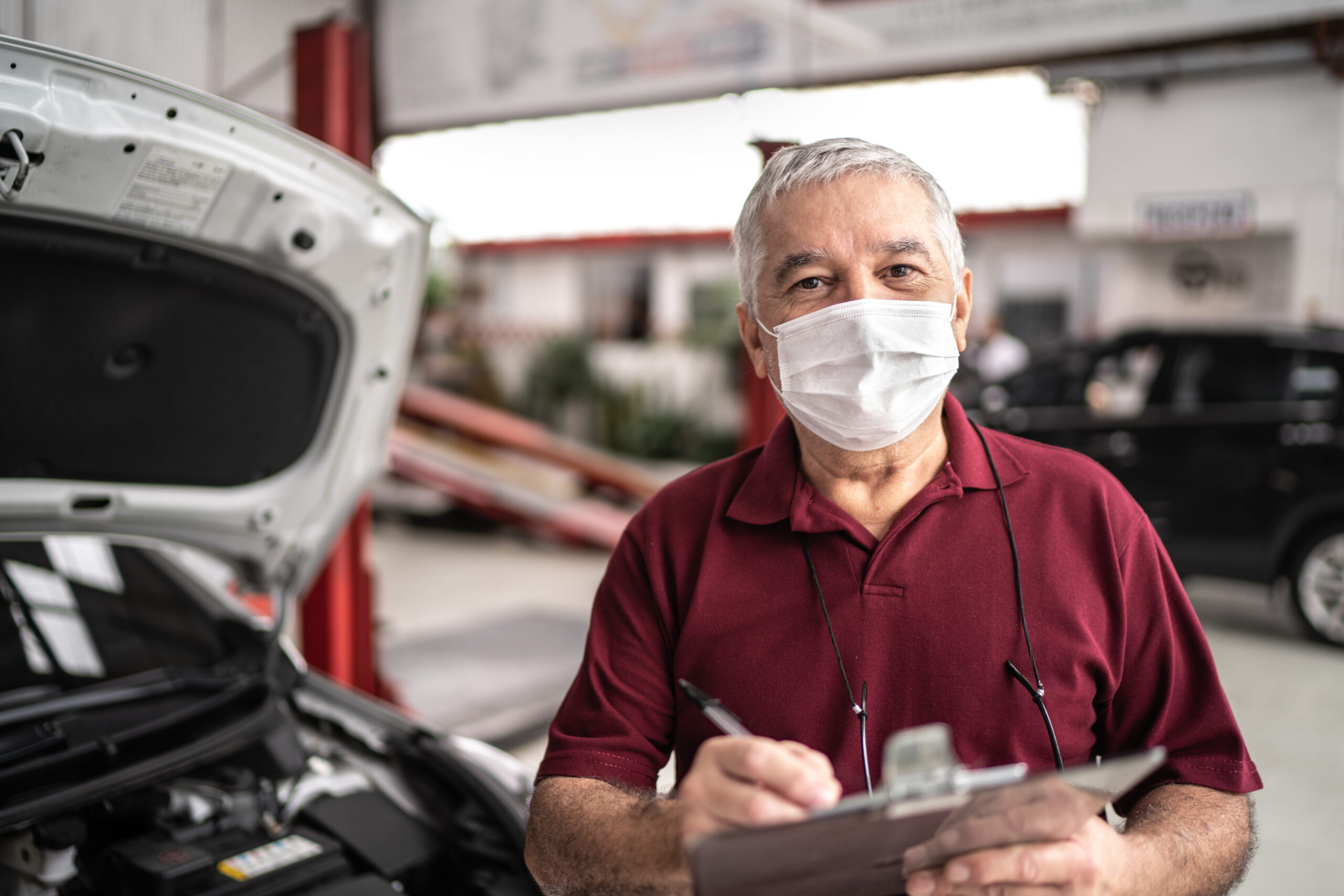 Portrait of auto mechanic senior man with face mask and conducting a safety audit at auto repair shop