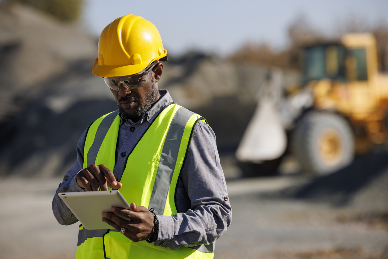 flex blueprint construction 1 Portrait of male engineer with hardhat using digital tablet while working at construction site